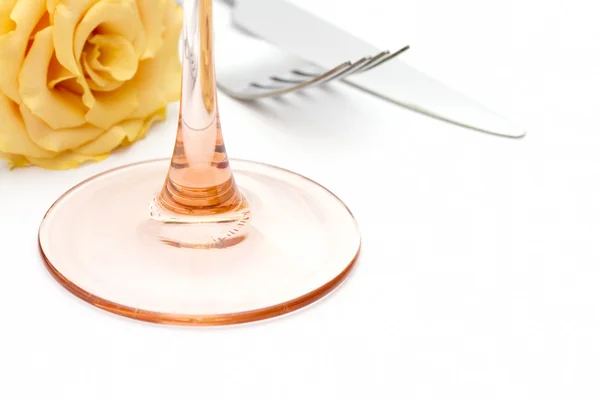 Cena lugar ajuste. Cuchillo y tenedor y vidrio con rosa amarilla sobre blanco — Foto de Stock