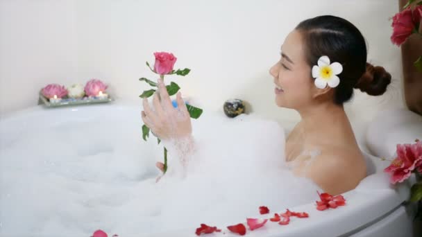 입니다 아름다운 아시아 여인이 거품이 비누와 꽃잎으로 긴장을 — 비디오