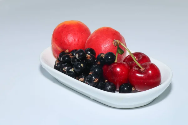 Beyaz bir arka planda sulu ve lezzetli kayısılar, kirazlar ve üzümler. Meyveler ve meyveler