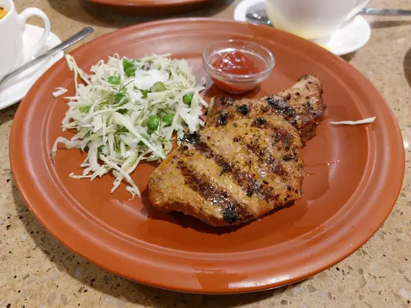 野菜サラダ付きの大きな茶色のプレートの上にコスティシンポークステーキ レストランでのおいしいディナー — ストック写真