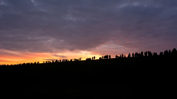 Linha de pessoas assistindo no pôr do sol — Fotografia de Stock