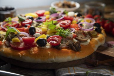 Pizza ve ahşap masada yemek pişirmek için malzemeler.