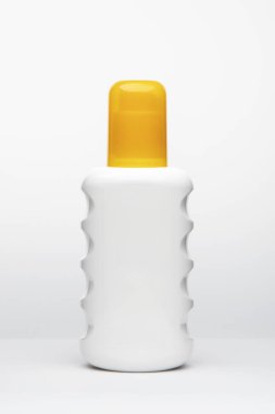 Beyaz arka planda sarı başlıklı beyaz plastik şişe.