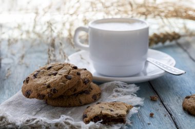 Chocolate chip cookies and a cup of latte on a blue wooden table