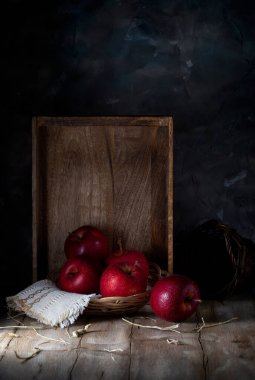 Red apples and a wooden box against the wall