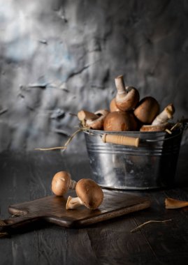Mushrooms in an aluminum bucket and on a cutting board