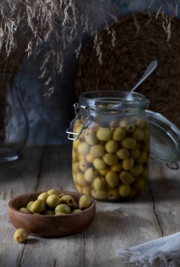 Ahşap bir masada zeytinli cam kavanoz