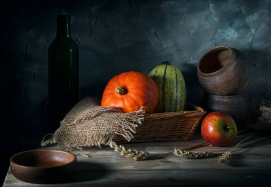 Tahta bir masada hasır sepetin içinde iki balkabağı.