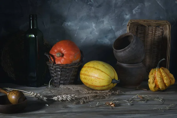 三个南瓜和一个木桌上的旧陶器 图库照片
