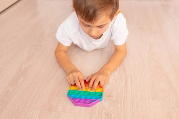 Renkli bir pop müziği çalan bir çocuk. Stres önleyici. Popüler rahatlatıcı romb şekilli silikon stres atma oyuncağı. Karantina ve kendini izole etme süresince çocuklar için oyunlar
