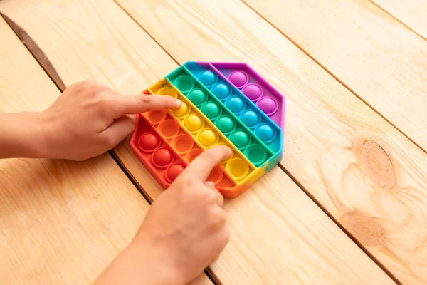 Renkli pop müziğiyle oynayan çocuk ellerini yakın plan çek. Stres önleyici. Popüler rahatlatıcı romb şekilli silikon stres atma oyuncağı. Karantina ve kendini izole etme süresince çocuklar için oyunlar