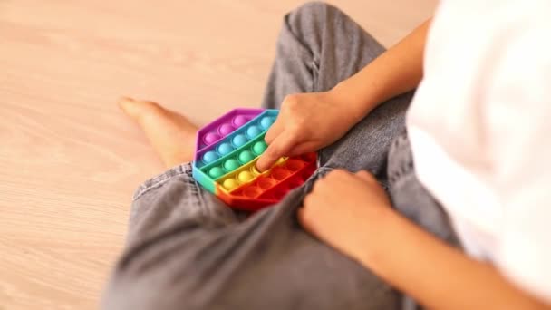 Uma criança com um colorido pop-lo jogo. Anti-stress. Popular Relaxante losango forma silicone alívio de estresse brinquedo. Jogos para crianças durante a quarentena e auto-isolamento — Vídeo de Stock