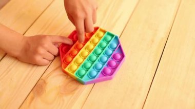 Renkli pop müziğiyle oynayan çocuk ellerini yakın plan çek. Stres önleyici. Popüler rahatlatıcı romb şekilli silikon stres atma oyuncağı. Karantina ve kendini izole etme süresince çocuklar için oyunlar