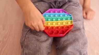 Renkli bir pop müziği çalan bir çocuk. Stres önleyici. Popüler rahatlatıcı romb şekilli silikon stres atma oyuncağı. Karantina ve kendini izole etme süresince çocuklar için oyunlar