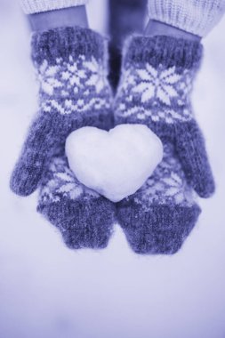 2022 Yılın Rengi Çok Peri. Avuçlarında kardan bir kalp tutan kırmızı eldivenli bir kız. Sevgililer Günü konsepti. Aşk ilanı. Yüksek kalite fotoğraf