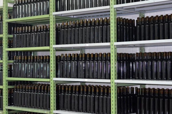 Wine production in traditional way in a wine cellar. Wine bottles on a shelf