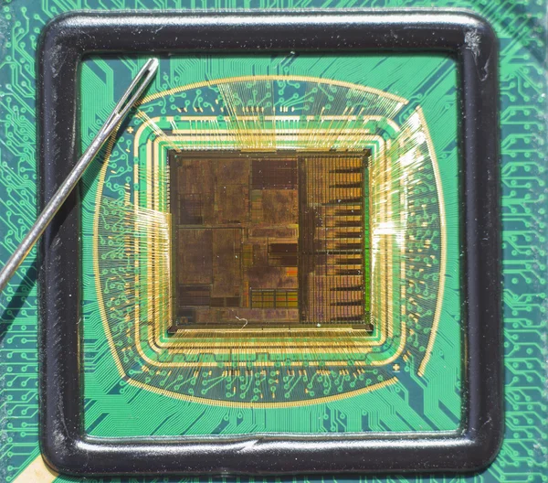 Offener Computerchip mit Golddraht-Anschlüssen im Vergleich zu einer Nadel — Stockfoto