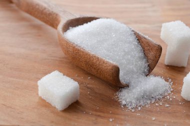 kristal granüle şeker tanecikleri ve beyaz şeker küpü arka planı masanın üzerinde