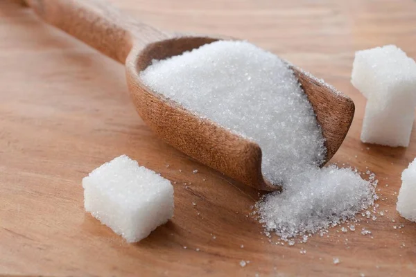 kristal granüle şeker tanecikleri ve beyaz şeker küpü arka planı masanın üzerinde