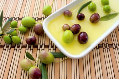 Kahverengi hasır arka planda beyaz bir tabakta zeytinyağı ve zeytin arkaplanı