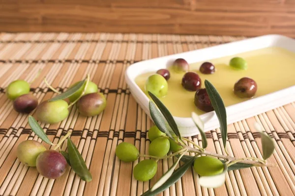 Olive oil on a white plate on a brown wicker background and olives background