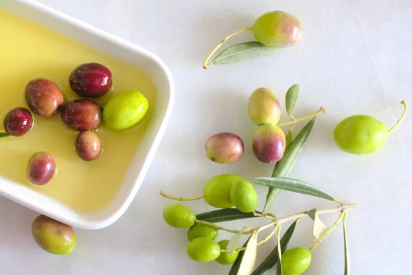 Olive oil on a white porcelain plate on a white background and olives background