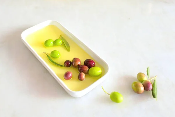 Olive oil on a white porcelain plate on a white background and olives background