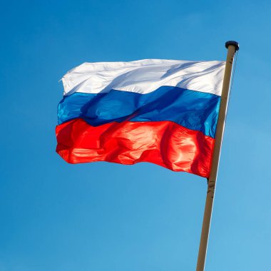 Mavi gökyüzüne karşı dalgalanan Rus bayrağı