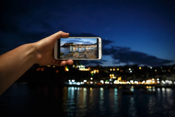 Ο άνθρωπος λήψη φωτογραφιών στο κινητό τηλέφωνο smartphone στο βράδυ της πόλης της θάλασσας — Φωτογραφία Αρχείου