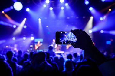 Müzik ve ışık gösterisi sırasında konser salonunda akıllı telefonlu eller.