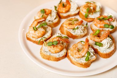 Beyaz tabakta karidesli küçük sandviçler.