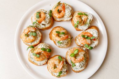 Beyaz tabakta karidesli küçük sandviçler.