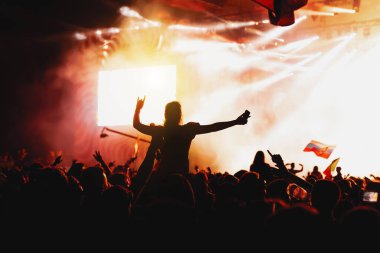 Kalabalıktaki bir kızın silueti açık hava müzik festivali konserinin keyfini çıkarıyor.