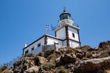 Mavi arka planda Yunanistan bayrağı olan eski deniz feneri