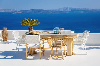 Thira, Santorini Adası, Yunanistan 'da dinlenmek için ahşap bir masa ve sandalyeli güneşli bir teras.