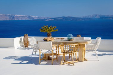 Thira, Santorini Adası, Yunanistan 'da ahşap bir masa ve sandalyeli bir güneş terası. Kalderanın üzerinde güzel bir dinlenme yeri.