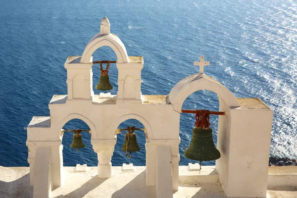 十字と村の鐘を持つ伝統的なギリシャの白い教会のアーチを通して穏やかな海の表面を見るキクラデス島サントリーニ島のオイアギリシャ — ストック写真