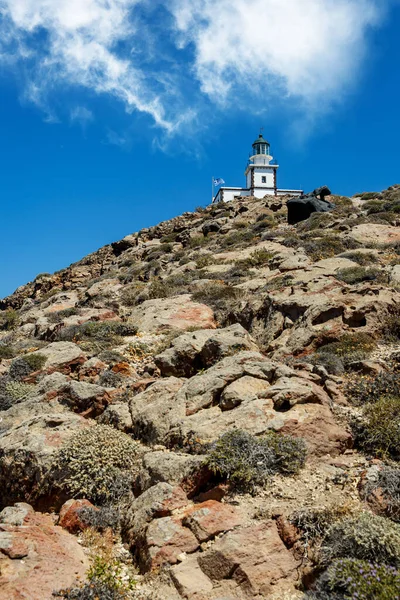 Kayalık deniz kıyısındaki eski deniz feneri. Bulutlu mavi gökyüzü
