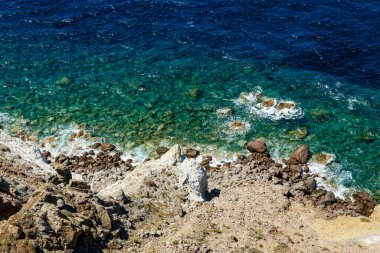 Mavi okyanusun kayalık kıyısı ve şeffaf su. Üst görünüm