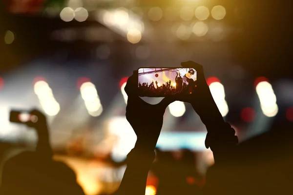 Music band fan holding the smart phone for photographing a concert