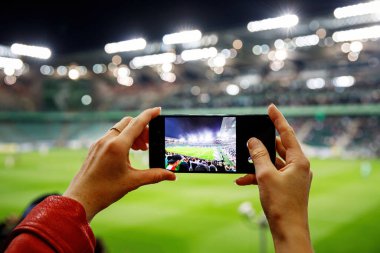 Akıllı telefondan futbol maçının fotoğrafını çeken bir hayran. Stadyumdaki cep telefonu kamerasını kullanarak.