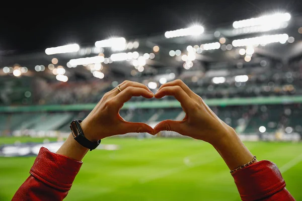 She loves this team. Heart shape for the favorite football club during a match in a stadium.