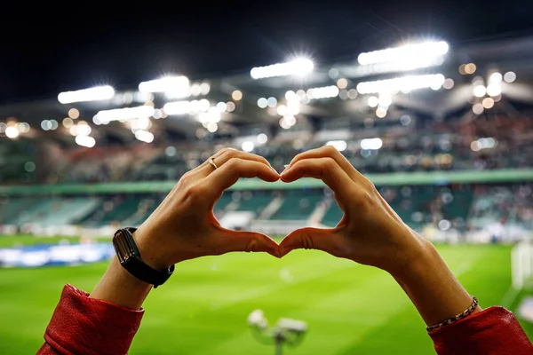 She loves this team. Heart shape for the favorite football club during a match in a stadium.