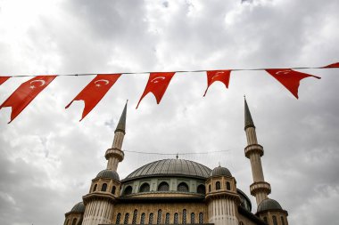 Cami yakınındaki Türk bayrakları. Arkaplanda minareler ve bulutlu gökyüzü