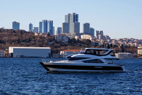 Modern bir şehir limanında lüks bir yat. Arkasında gökdelenler olan İstanbul şehri