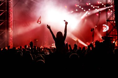 İnsanlar yaz festivali partisinde dans edip eğleniyorlar. Elleri havada, konser etkinliğini kutluyorlar.