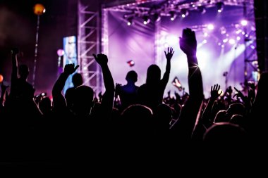 Bir konser etkinliğinde ellerini kaldıran erkek ve kadınlar