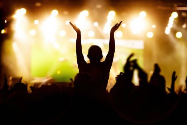 Kalabalık, mutlu insanlar rock konserinden zevk alıyor, ellerini kaldırıp zevkle alkışlıyorlar..