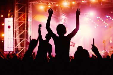 Rock konserindeki insanların silueti parlak sahne ışıkları önünde. Yaz müzik festivalinde zevk