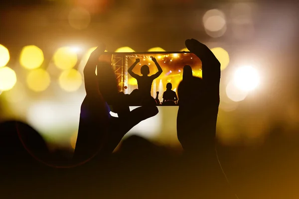 Recording a concert with mobile phone, silhouette of hands with smartphone